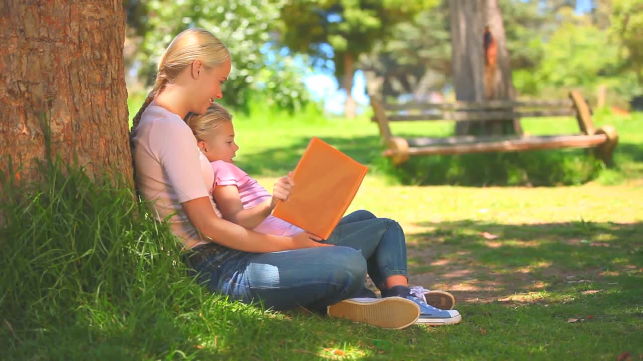 어린 여자 가 딸 과 함께 책 을 읽고 있다