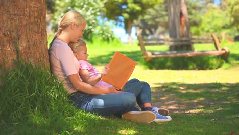 Mujer-Joven-Leyendo-Un-Libro-Con-Su-Hija