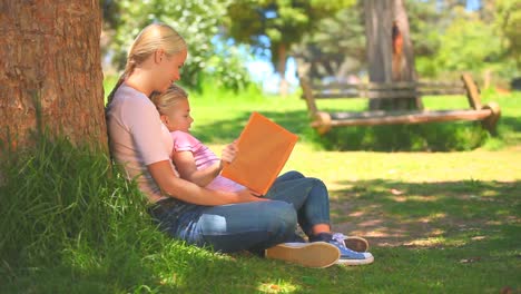 young woman reading a book with her daughter