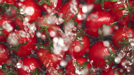 Zeitlupe-Roter-Kirschtomaten,-Die-Auf-Die-Wasseroberfläche-Fallen-Und-Spritzen