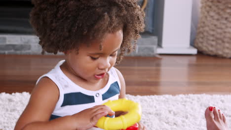 young black girl playing with plastic rings in sitting room