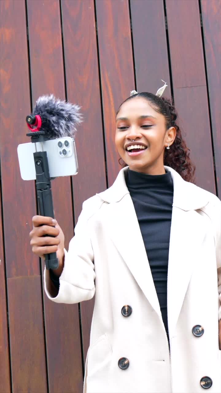 A woman recording a vlog with her phone and microphone