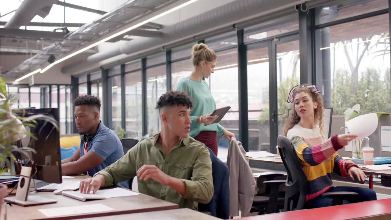 Happy diverse casual business colleagues working at computers and passing document, slow motion