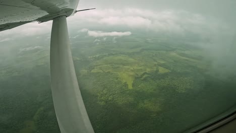 Wing-support-of-single-engine-airplane-over-farmland-countryside-in-Costa-Rica,-Cockpit-window-view