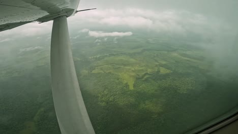 wing support of single engine airplane over farmland countryside in costa rica, cockpit window view