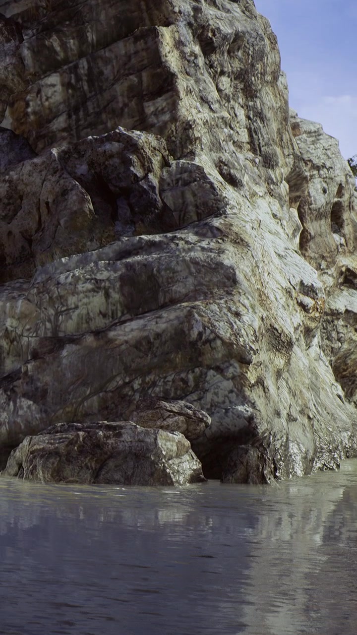 Rocce si ergono vicino all'acqua sotto un cielo blu in una località naturale.