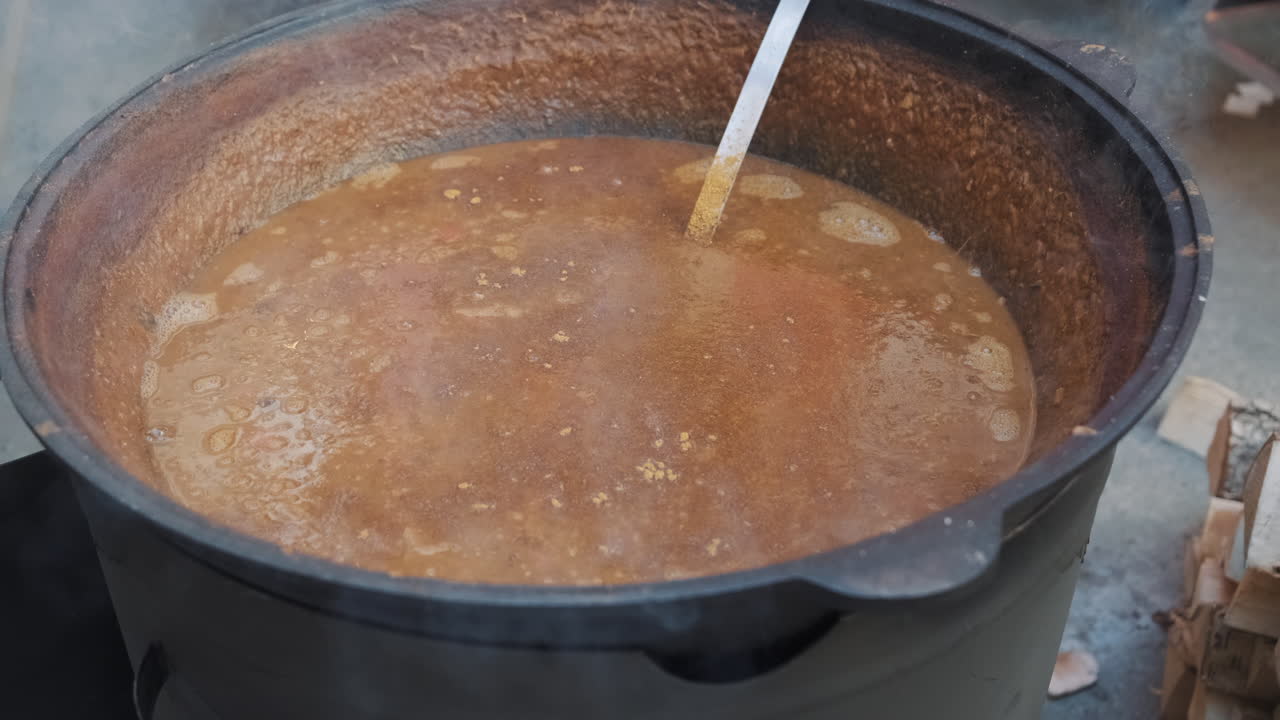 una gran olla de guiso abundante cocinando al aire libre