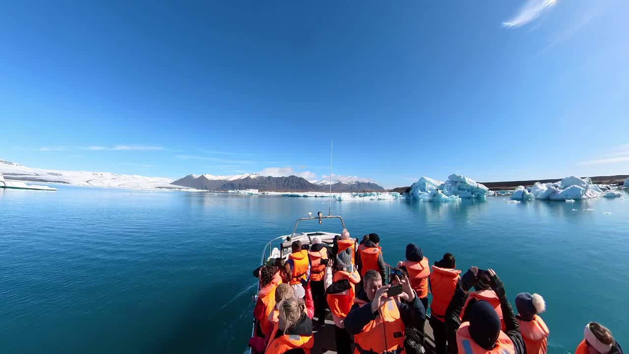 As travelers observe the serene magnificence of Iceland's snowy paradise, bordered by frosty mountains and a vibrant sky.
