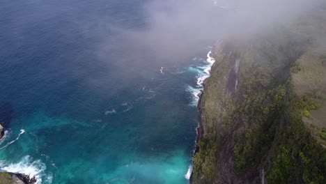 wonderful aerial view flight hover drone shot in over clouds high in sky
kelingking beach at nusa penida in bali indonesia is like jurassic park