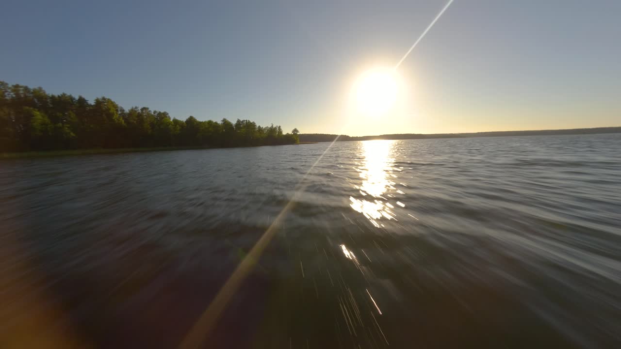 리투아니아의 발루오사스 호수 위의 낮은 고도 드론 비행과 해가 지면서 강한 렌즈 플레어