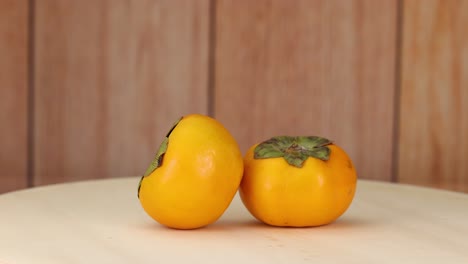 two persimmons arranged on a wooden surface