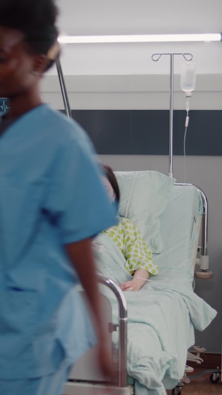 Vertical video: Afro american nurse arrange sick woman bed during medical recovery