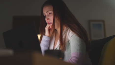 Anxious-Woman-Sitting-On-Sofa-At-Home-At-Night-Looking-At-Laptop-Concerned-About-Social-Media-Or-Bad-News-8