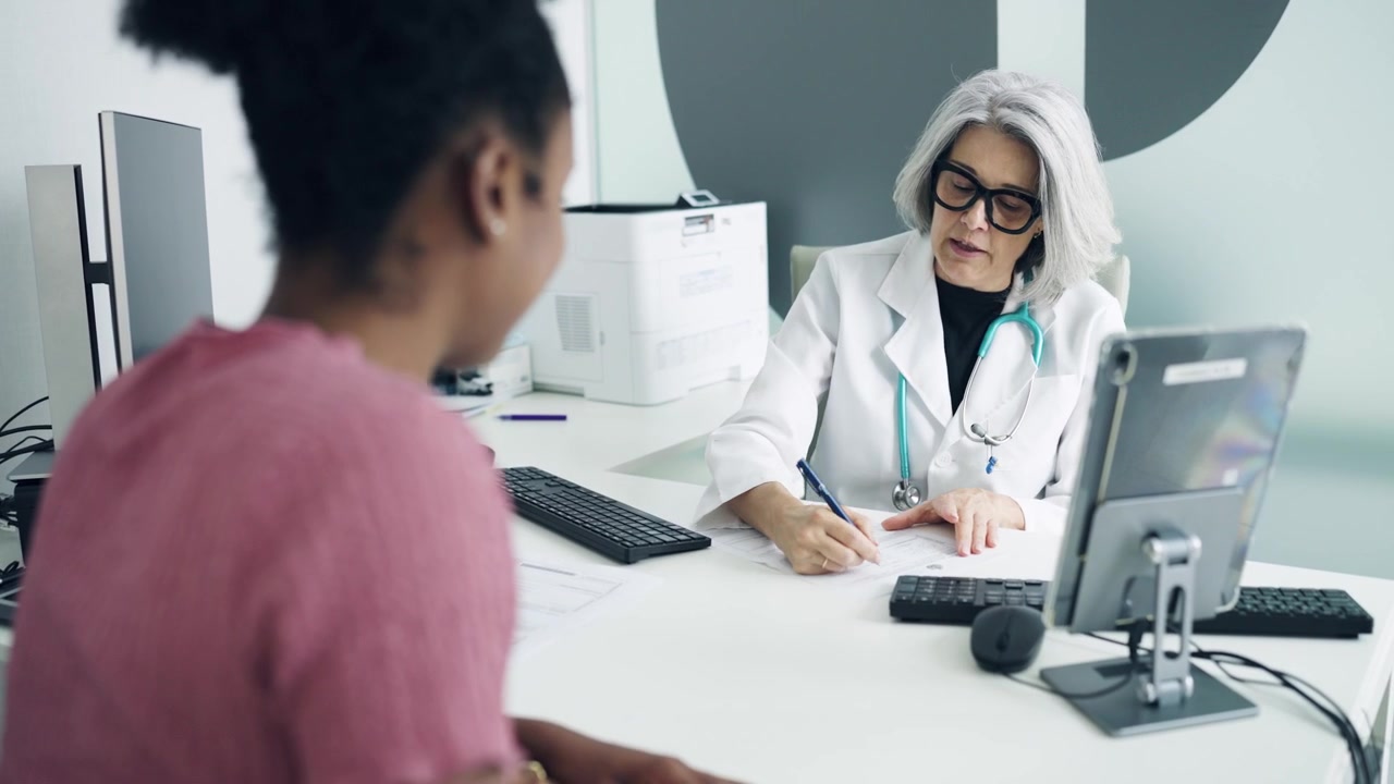 Erfaren kvindelig læge i konsultation med patient på lægekontoret