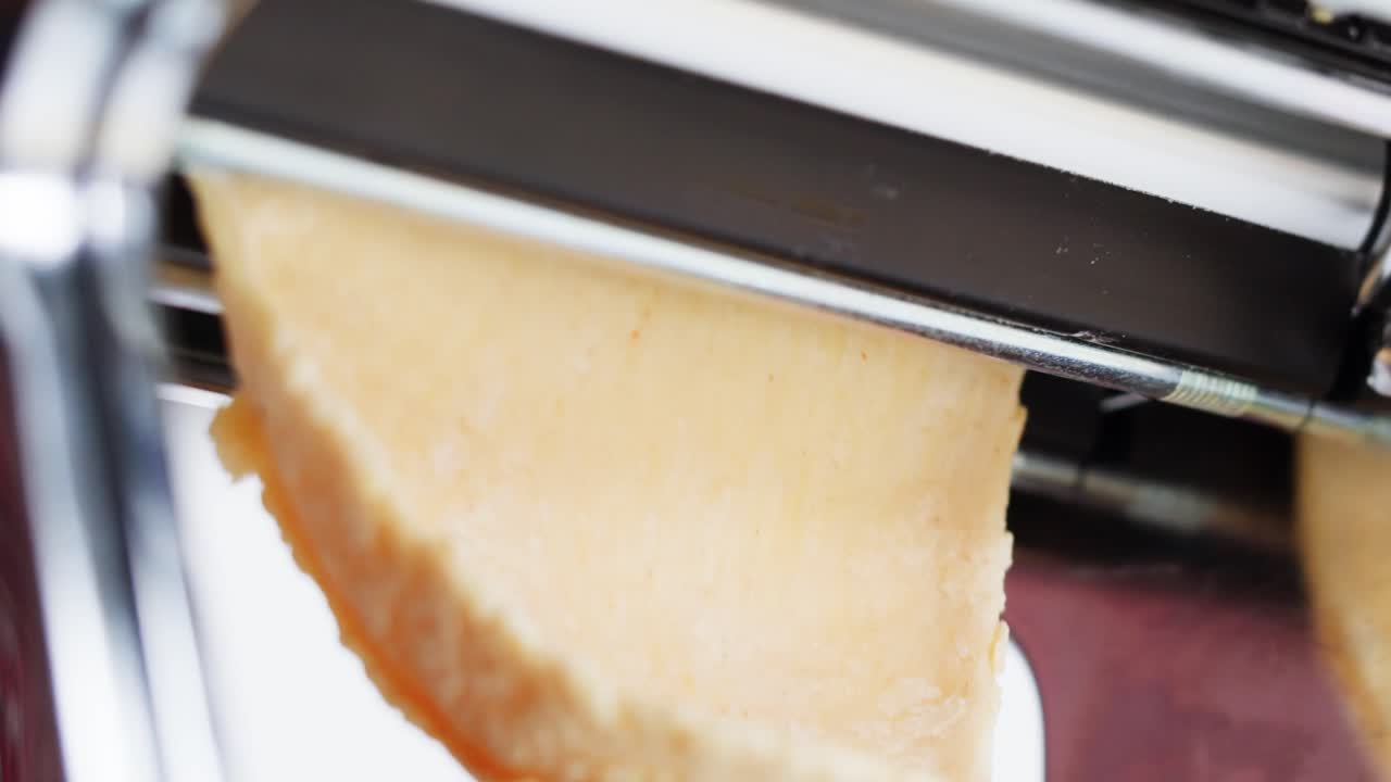 Close-up of Pasta Dough Being Rolled Through a Pasta Machine