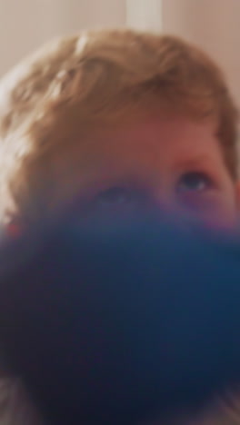 angry toddler in boxer gloves waves hands punching hanging bag in gym. emotional little boy opens mouth practicing boxing skills closeup slow motion