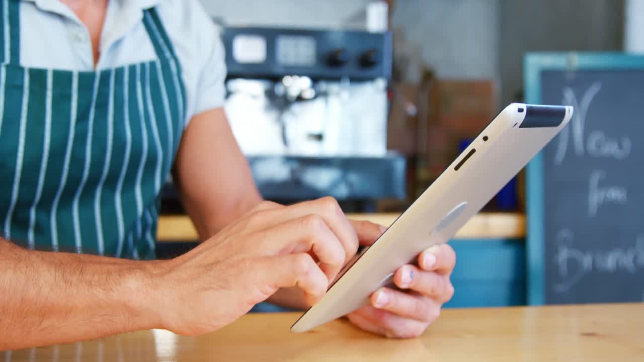 Waiter is using a tablet on counter