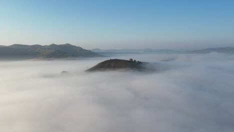 hill top surrounded by fog in the autumn morning romanian remote countryside. 4k aerial drone video.