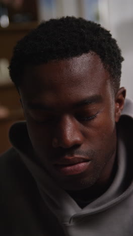 vertical video close up shot of unhappy and depressed young man sitting on sofa shaking head and shouting