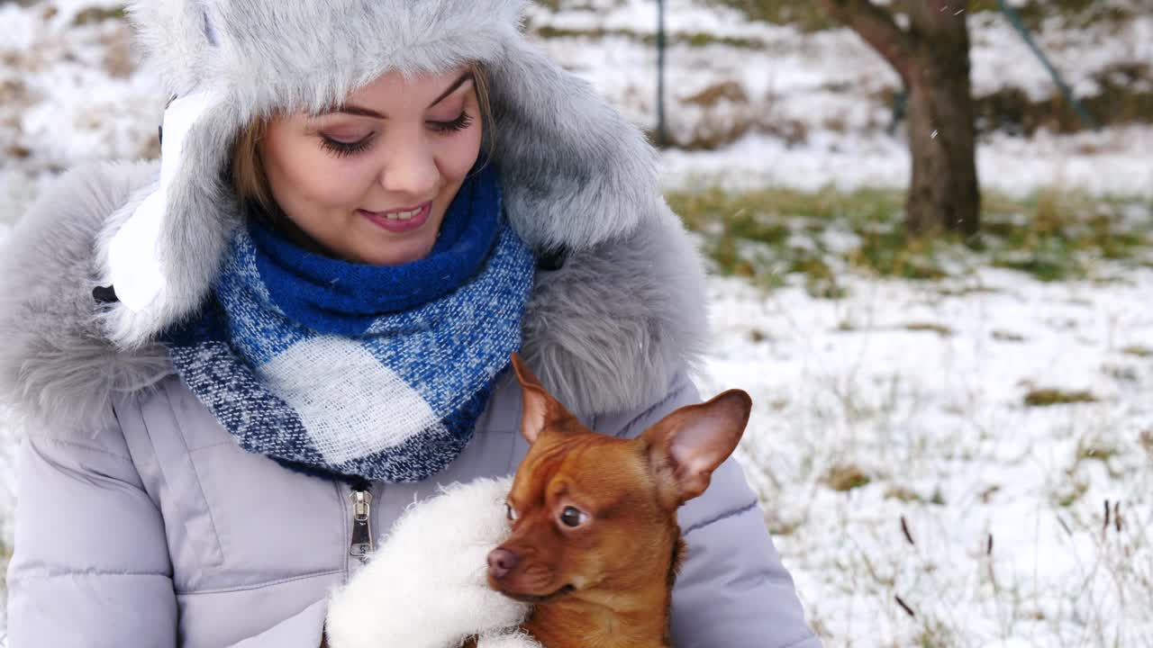여자 는 겨울 밖 에서 작은 개 와 함께 놀고 있다