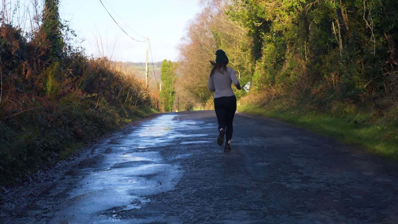 Runner on a quiet country road in sunny weather, enjoying a peaceful jog