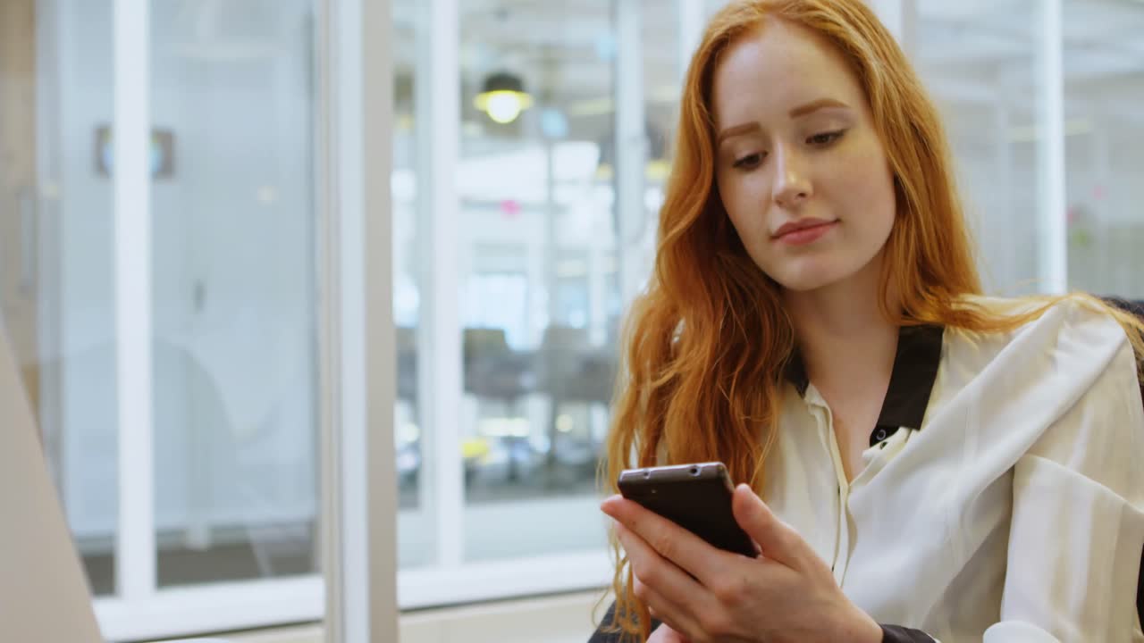 Female executive using mobile phone in office 4k