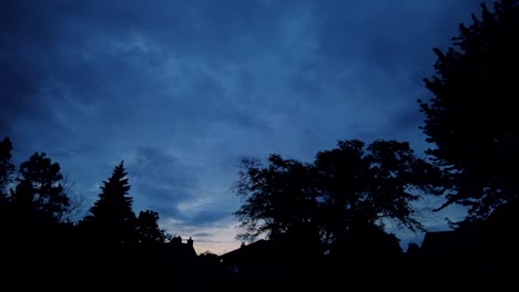 Sunset-in-the-late-evening-against-a-silhouette-of-a-tree-line,-timelapse