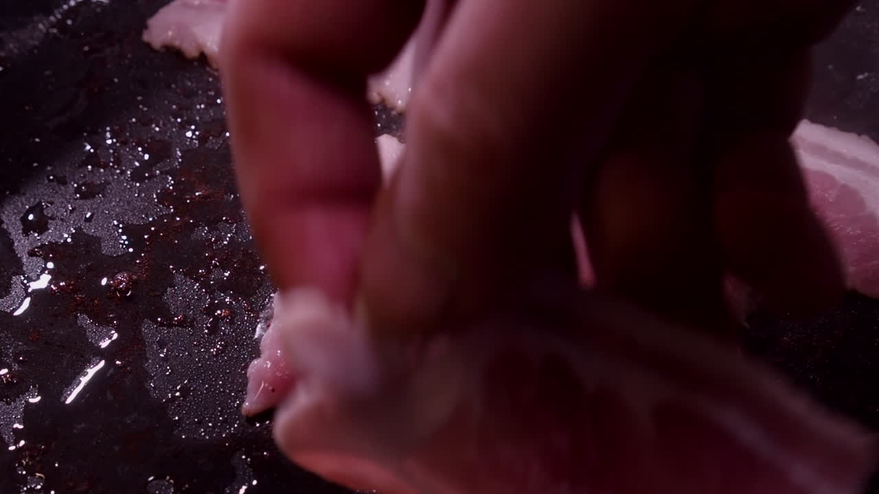 primer plano en movimiento rápido: las rebanadas de tocino graso se encogen a medida que se cocinan en la sartén