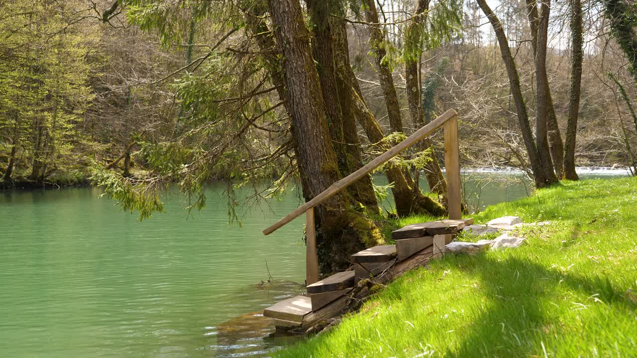 Tomada estática de escadas de madeira que levam aos banhos naturais no Rio Krka