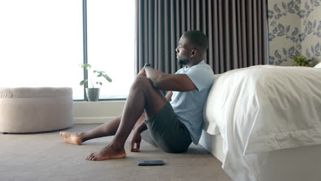 relaxing at home, man sitting on floor beside bed, smartphone nearby