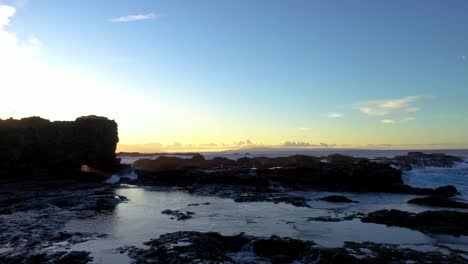 Aerial-from-Lanai-south-shore-over-rugged-coastal-rocks-toward-Sweetheart-Rock-in-Pu'Upehe-Islet-Seabird-Sanctuary-at-sunset