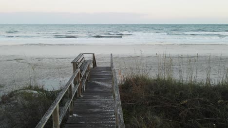 Still-shot-of-beach-walk-with-birds-and-waves-in-background-at-sunset