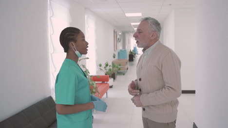 an old man with a beard and gray hair thanks for the care provided to a young female doctor in the hospital