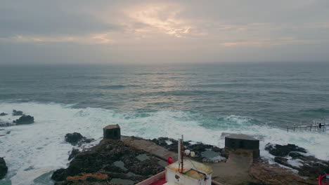 cloudy sky ocean lighthouse aerial view. beacon at rocky coast washed foamy sea