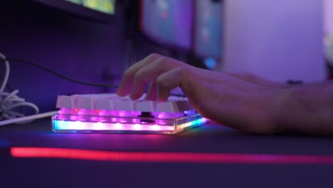 close up of the hand of a human playing pc games on a led multicolored keyboard in an internet cafe