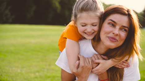 Linda-Hijita-Abrazando-A-Su-Feliz-Madre-Desde-Atrás-En-El-Parque