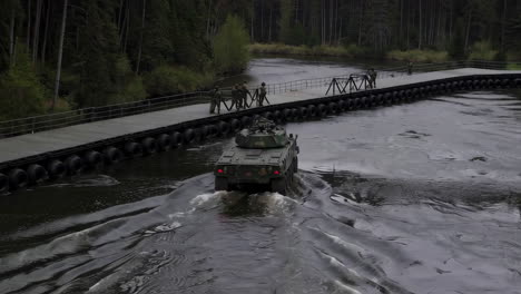 military forces crossing a river using a floating bridge
