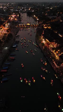 aerial view of breathtaking lit up boats on the hoai river during the hoi an lantern boat celebration, vertical video