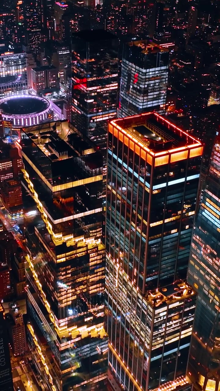 Nova York, a cidade que nunca dorme, com bilhões de luzes acesas nas ruas e edifícios. Vista noturna do centro da cidade do alto. Vídeo vertical.