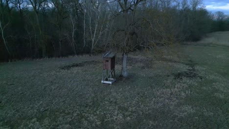 wooden hunting tower under the tree in the wilderness. low aerial orbit