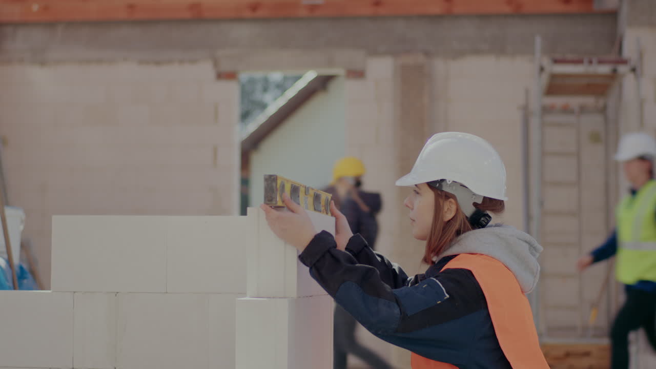 Lockdown shot of confident young female construction worker analyzing concrete wall with level at site