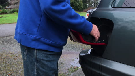 man removing tail light of a car