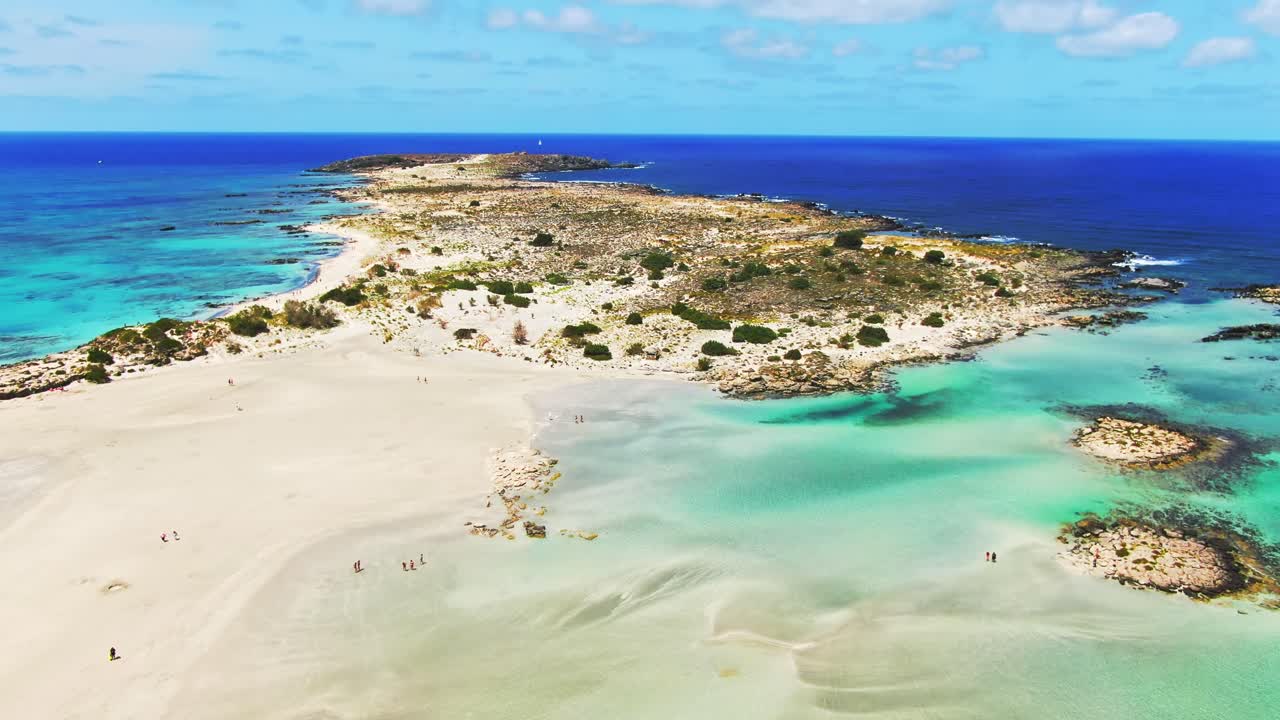 Slow aerial panning shot above Elafonissi beach with azure water and shallow lagoon, Crete - Greece