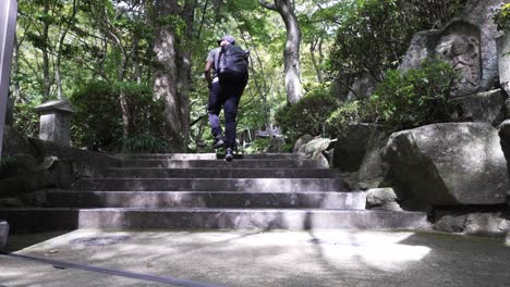 low angle shot of solo male traveller walking up steps in japanese zen garden in mitaki
