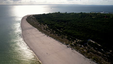 Toma-Cinematográfica-De-Drones-De-Una-Playa-De-Arena-Con-Mar-Báltico-Y-Reflejo-Del-Sol-Al-Atardecer-En-Hel,-Polonia.