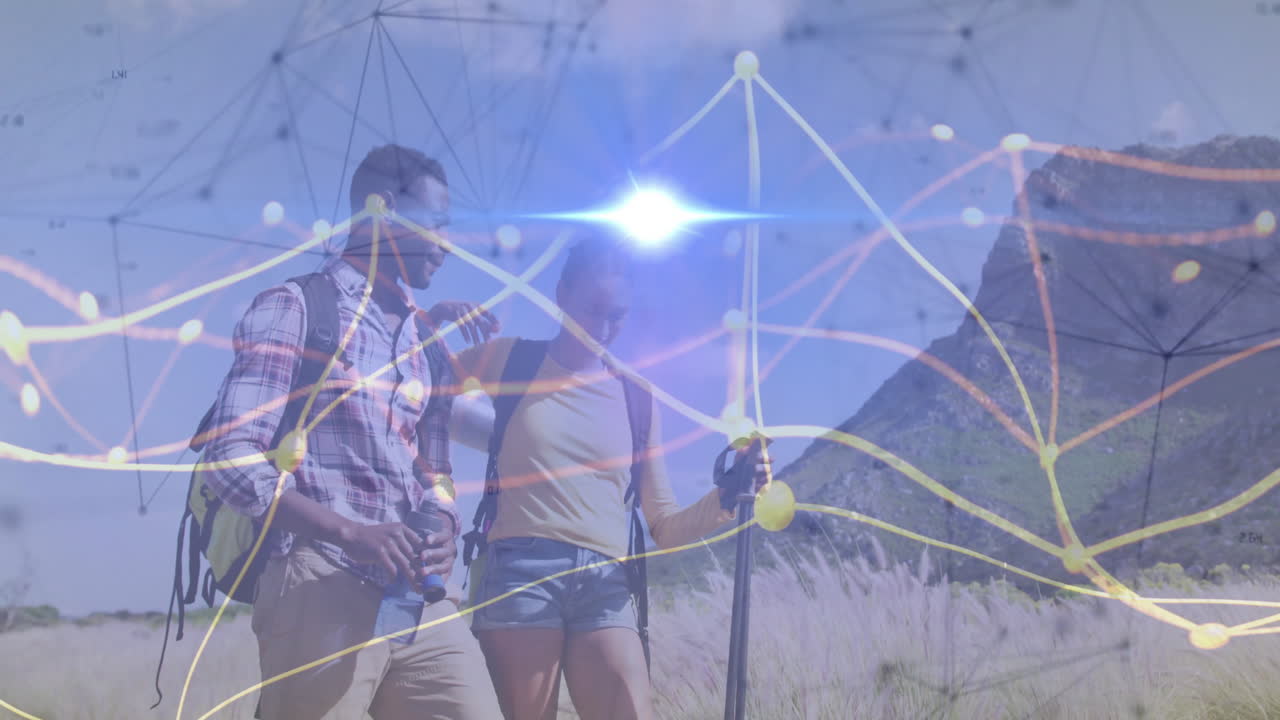 Two hikers trekking mountain grassland trail, displaying floating technology network data graphics