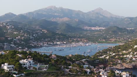 Vista-Aérea-Del-Complejo-Turístico-Con-Bahía,-Fondo-Pintoresco-De-Montaña,-Mallorca