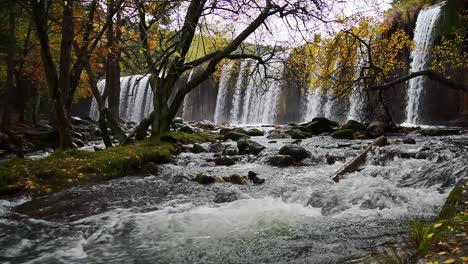 waterfall and river in autumn woodland