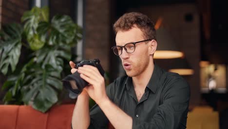 stylish young handsome man sitting in a cafe watching a video on a slr camera