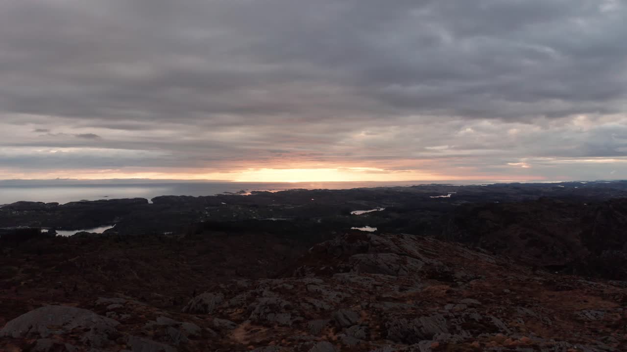 costa de noruega al amanecer - antena inversa con puesta de sol nublada - mar del norte al fondo con un oscuro paisaje montañoso delante
